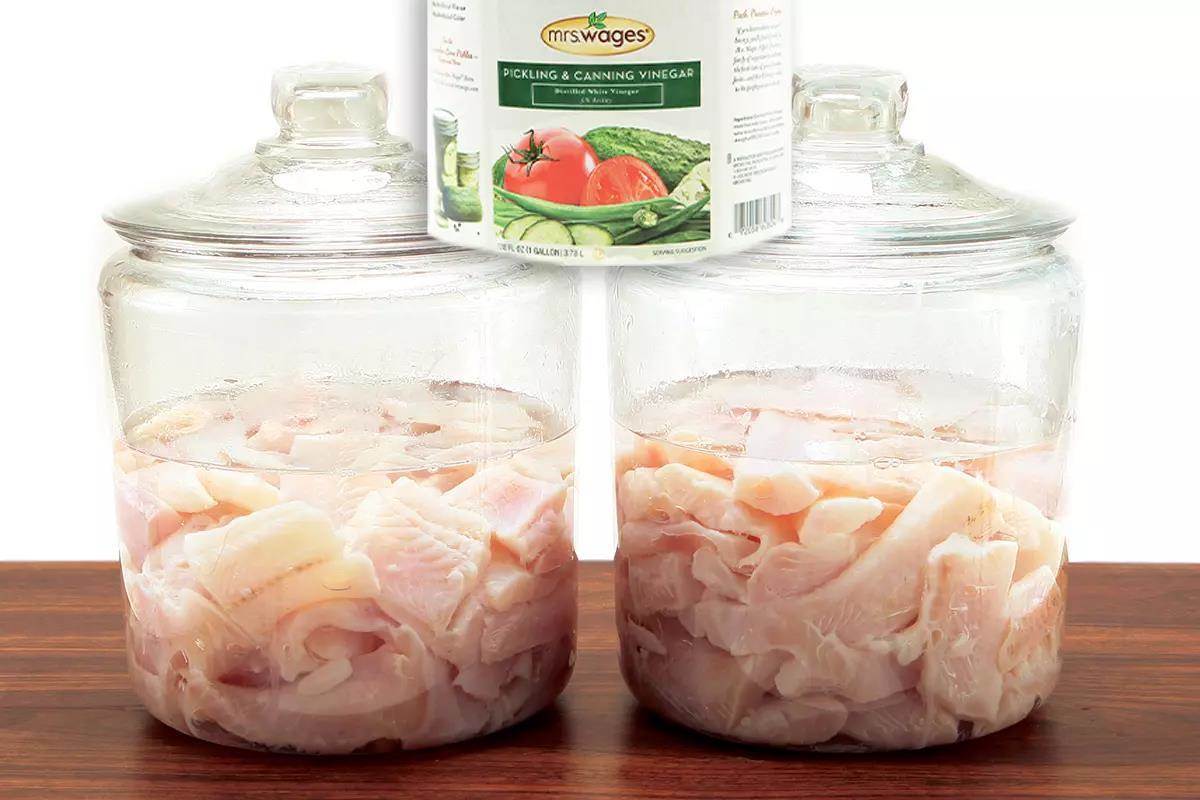 Two lidded jars that have fish fillets and vinegar; a vinegar jar label on top.